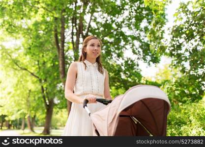 family, motherhood and people concept - happy mother with child sleeping in stroller walking at summer park. happy mother with child in stroller at summer park