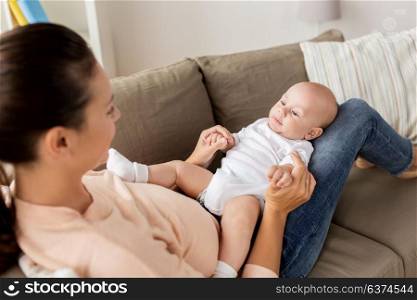 family, motherhood and people concept - happy mother with little baby boy lying on sofa at home. happy mother with little baby boy at home