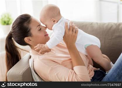 family, motherhood and people concept - happy mother with little baby boy lying on sofa at home. happy mother with little baby boy at home