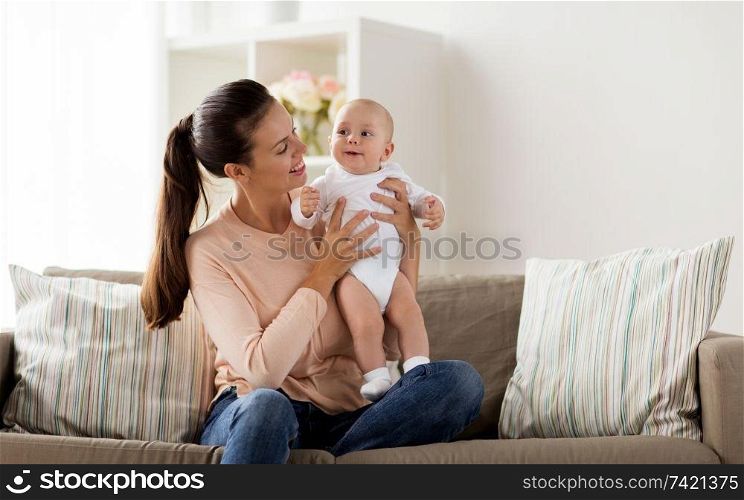 family, motherhood and people concept - happy mother with little baby boy sitting on sofa at home. happy mother with little baby boy at home