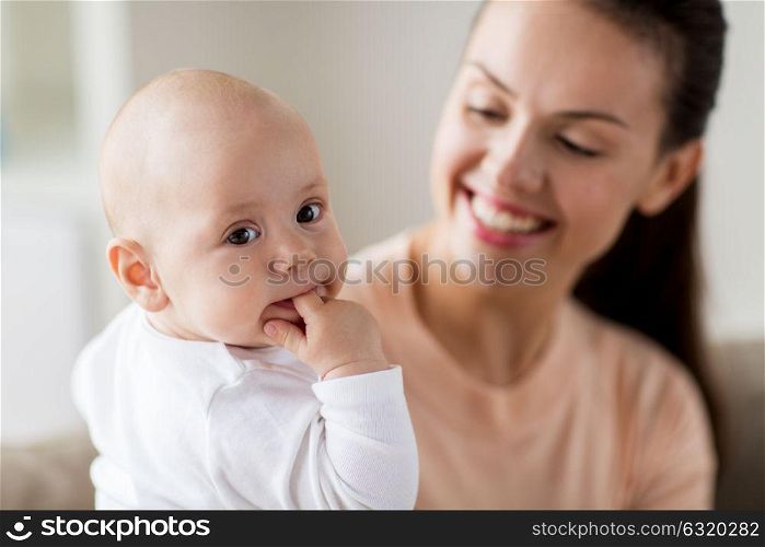 family, motherhood and people concept - happy mother with little baby boy sucking finger. happy mother with little baby boy at home