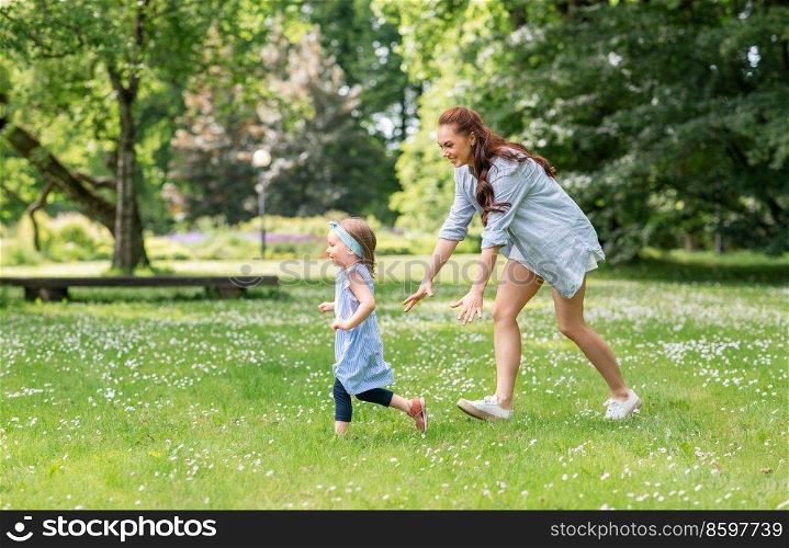 family, motherhood and people concept - happy mother with little daughter playing at summer park or garden. happy mother with little daughter playing at park