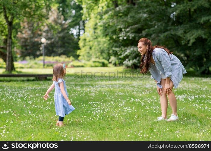 family, motherhood and people concept - happy mother with little daughter playing at summer park or garden. happy mother with little daughter playing at park