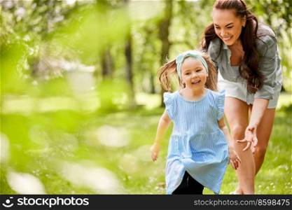 family, motherhood and people concept - happy mother with little daughter playing at summer park. happy mother with little daughter playing at park