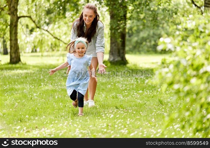 family, motherhood and people concept - happy mother with little daughter playing at summer park. happy mother with little daughter playing at park