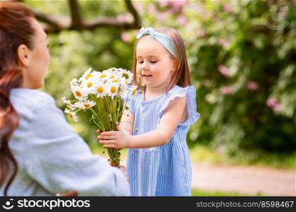 family, motherhood and people concept - happy mother with little daughter with chamomile flowers at summer park or garden. happy mother and daughter with chamomiles at park