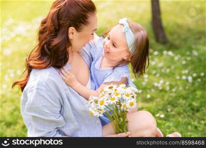 family, motherhood and people concept - happy mother with little daughter with chamomile flowers at summer park or garden. happy mother and daughter with chamomiles at park