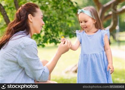family, motherhood and people concept - happy mother with little daughter with flowers at summer park or garden. happy mother and daughter with flowers at park