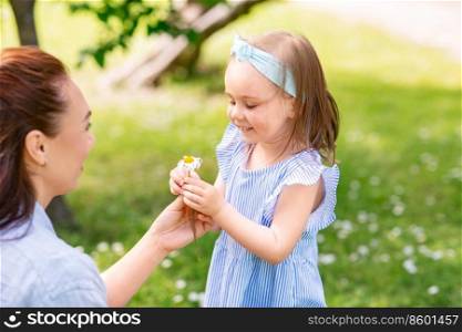 family, motherhood and people concept - happy mother with little daughter with flowers at summer park or garden. happy mother and daughter with flower at park