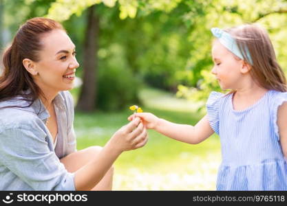 family, motherhood and people concept - happy mother with little daughter with flowers at summer park or garden. happy mother and daughter with flowers at park