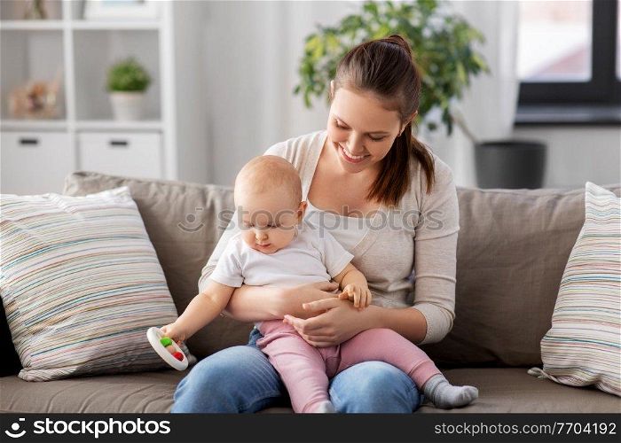 family, motherhood and people concept - happy smiling mother and little baby playing with rattle at home. mother and little baby playing with rattle at home