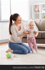 family, motherhood and people concept - happy smiling mother playing with little baby daughter on floor at home. happy mother playing with little baby at home