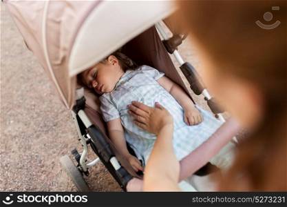 family, motherhood and people concept - mother with child sleeping in stroller. mother with child sleeping in stroller
