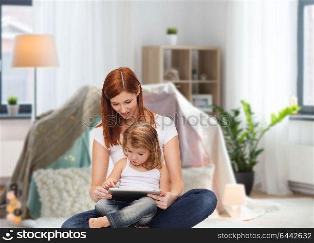 family, motherhood and technology concept - happy mother with adorable little daughter and tablet pc computer at home over kids room and tepee background. happy mother with little daughter and tablet pc