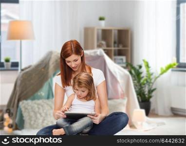 family, motherhood and technology concept - happy mother with adorable little daughter and tablet pc computer at home over kids room and tepee background. happy mother with little daughter and tablet pc