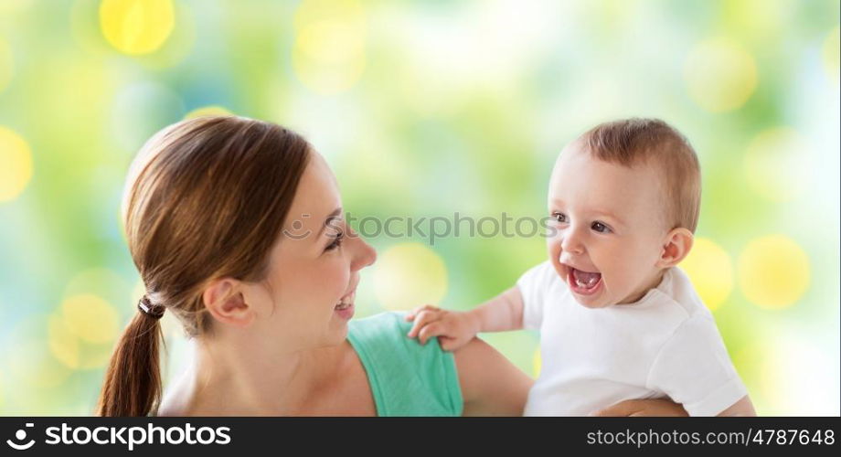 family, motherhood, child and parenthood concept - happy smiling young mother with little baby over green lights background