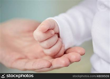 family, motherhood, parenting, people and child care concept - close up of mother and newborn baby hands