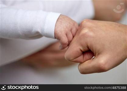 family, motherhood, parenting, people and child care concept - close up of mother and newborn baby hands making fist bump gesture