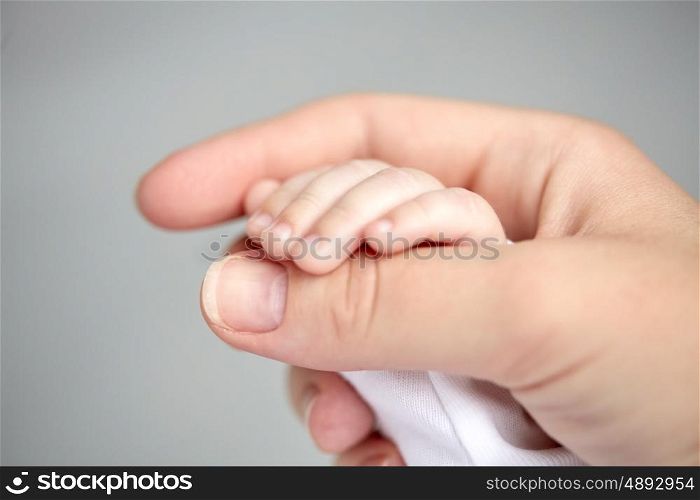 family, motherhood, parenting, people and child care concept - close up of mother and newborn baby hands