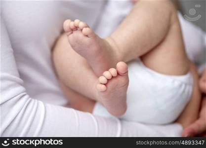 family, motherhood, parenting, people and child care concept - close up of newborn baby in mother hands