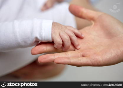 family, motherhood, parenting, people and child care concept - close up of mother and newborn baby hands