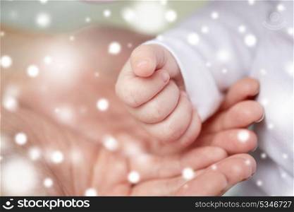 family, motherhood, parenting, people and child care concept - close up of mother and newborn baby hands over snow. close up of mother and newborn baby hands