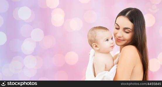 family, motherhood, parenting, people and child care concept - happy mother holding adorable baby over violet lights background