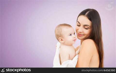 family, motherhood, parenting, people and child care concept - happy mother holding adorable baby over violet background