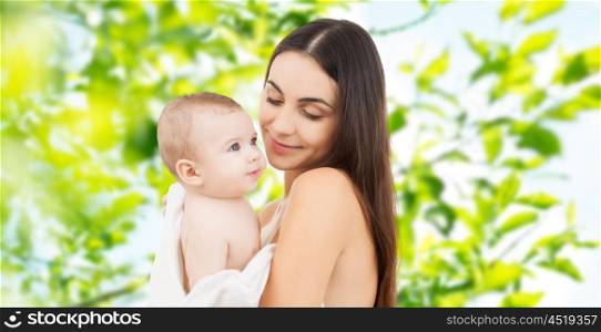 family, motherhood, parenting, people and child care concept - happy mother holding adorable baby over green natural background