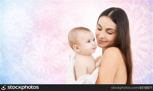 family, motherhood, parenting, people and child care concept - happy mother holding adorable baby over rose quartz and serenity patterned background