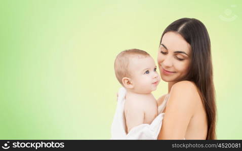 family, motherhood, parenting, people and child care concept - happy mother holding adorable baby over green background