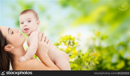 family, motherhood, parenting, people and child care concept - happy mother holding adorable baby over green natural background