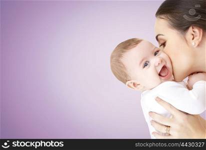 family, motherhood, parenting, people and child care concept - happy mother kissing adorable baby over violet background