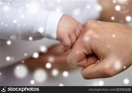 family, motherhood, people and child care concept - close up of mother and newborn baby hands making fist bump gesture over snow. close up of mother and newborn baby hands
