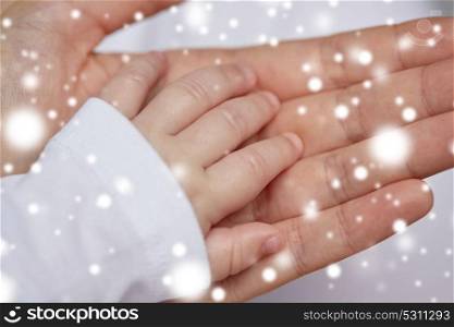 family, motherhood, people and child care concept - close up of mother and newborn baby hands over snow. close up of mother and newborn baby hands
