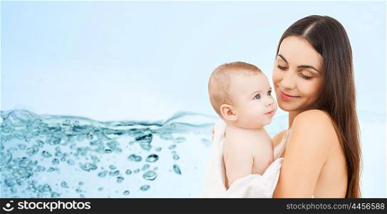 family, motherhood, people and child care concept - happy mother holding adorable baby over blue background with water splash