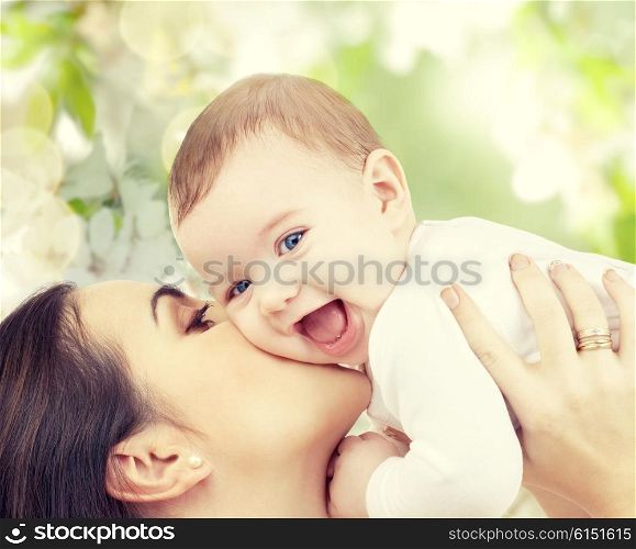 family, motherhood, spring, summer and people concept - happy laughing baby playing with mother over green blooming garden background