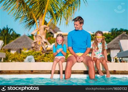Family of dad and little kids relaxing in swimming pool. Happy family of four in outdoors swimming pool