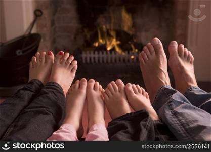 Family of feet warming at a fireplace