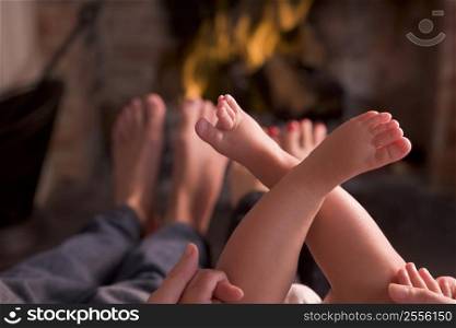 Family of feet warming at a fireplace