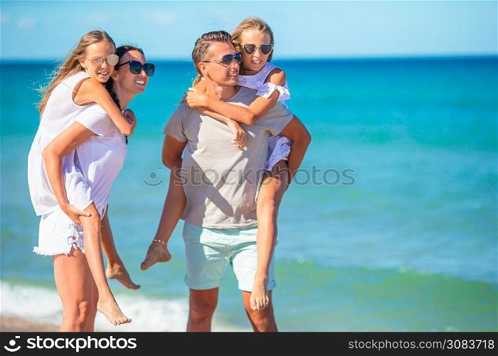 Family of four having fun together on the beach. Young family on vacation have a lot of fun