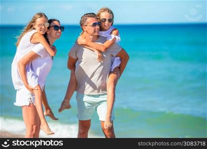Family of four having fun together on the beach. Young family on vacation have a lot of fun