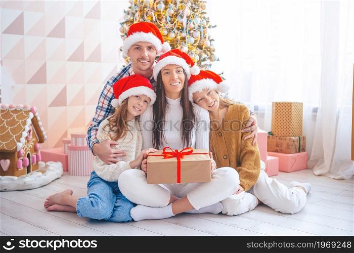 Family of four on Christmas holidays at home. Merry Christmas and Happy Holidays.. Happy young family with kids holding christmas presents