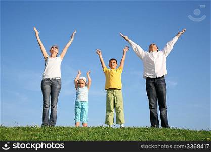 family of four on grass with hands up