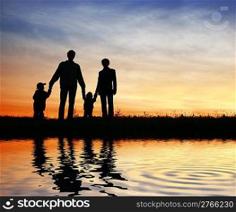 family of four on sunset sky, water
