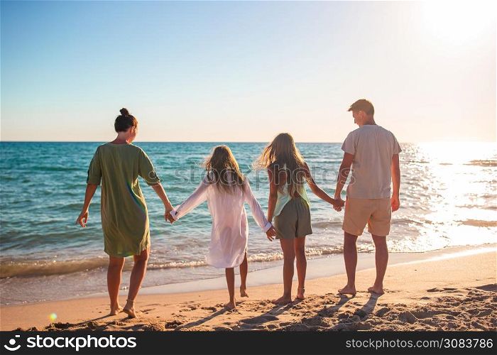 Family of four on the beach vacation on the sunset. Young family on vacation have a lot of fun