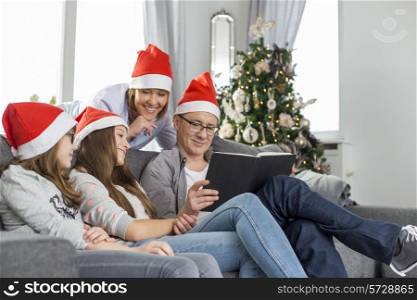 Family of four reading book in living room during Christmas