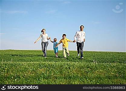 family of four running grass sky