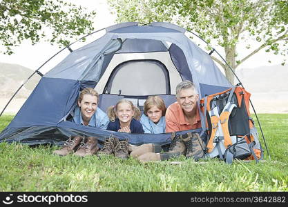 Family of four smiling from a tent