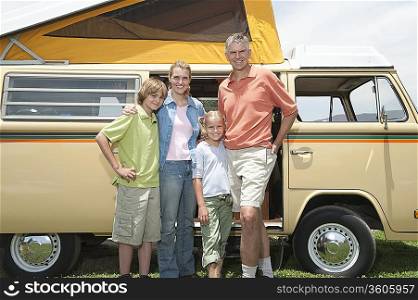Family of four stand at campervan